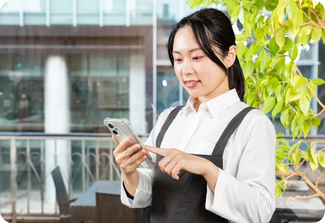 店員女性がスマホでマニュアルを確認する様子